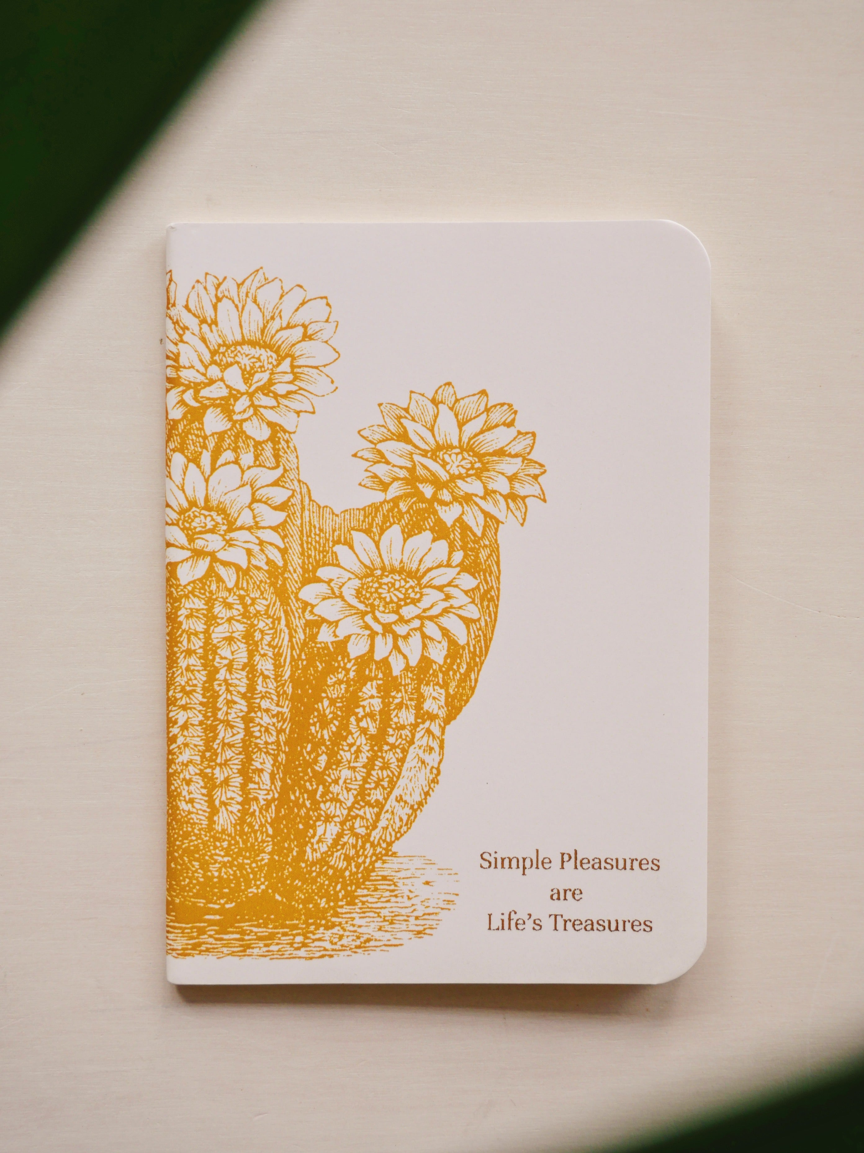 Notebook with yellow floral cactus design and text on a beige background