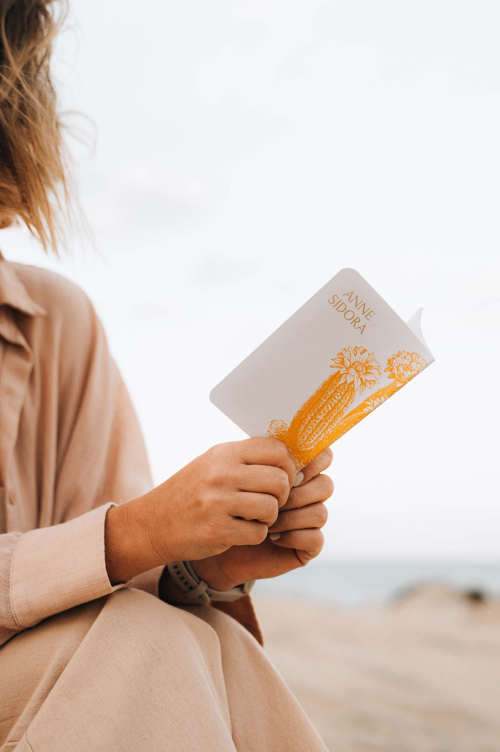 Person holding a notebook with a blurred beach background
