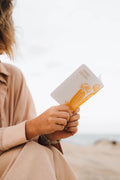 Person holding a notebook with a blurred beach background