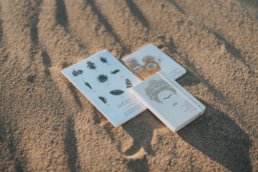 Three small notebooks from Mexico  on a sandy surface.