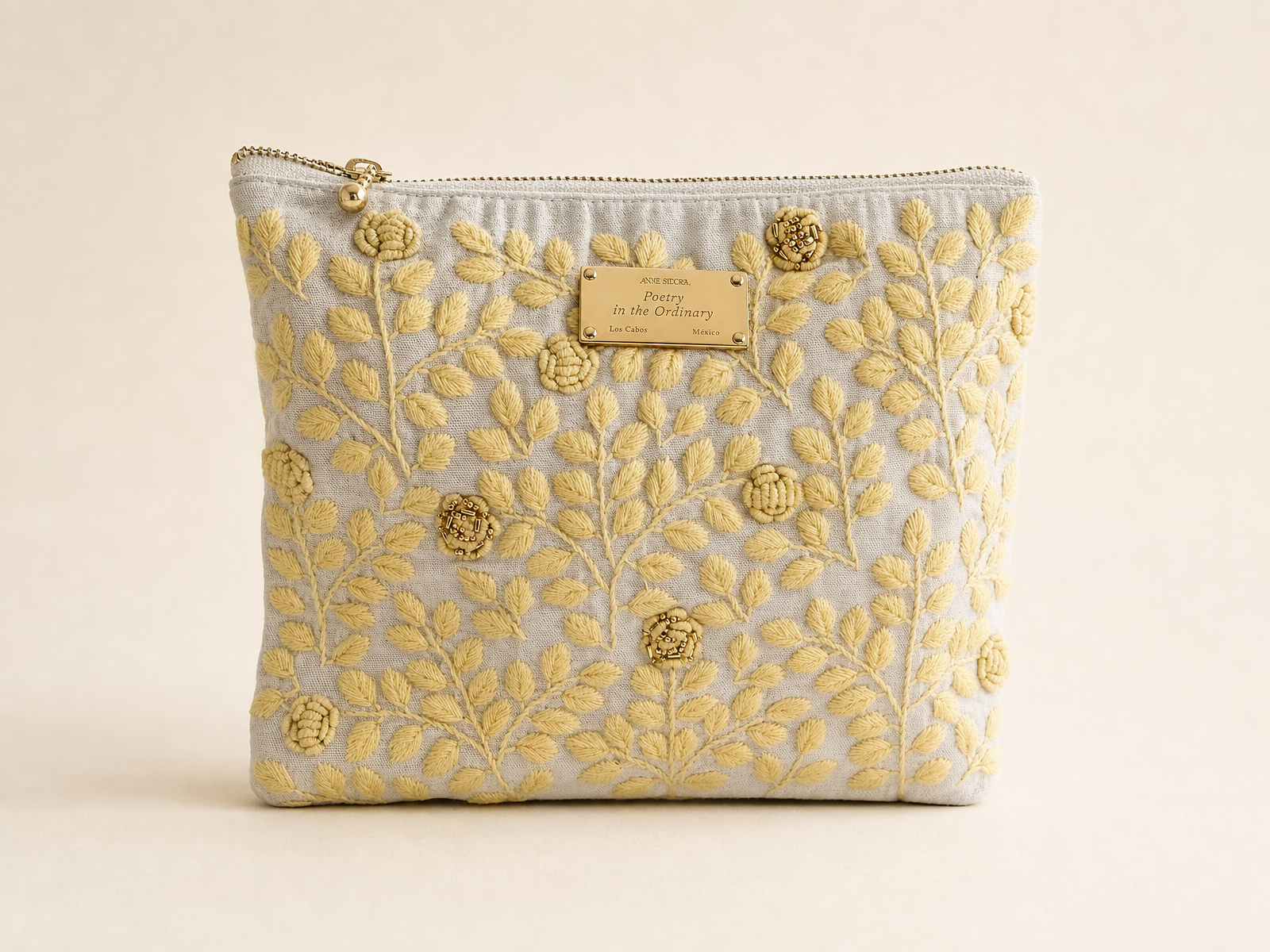 Rosa de Día embroidered pouch angled view showing butter yellow floral embroidery